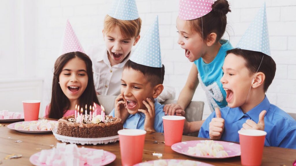 kids birthday party boy blowing out candles on cake